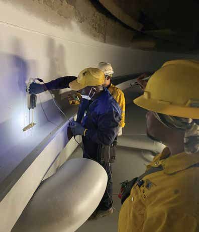 Inspectors examining a pipe surface with handheld lighting