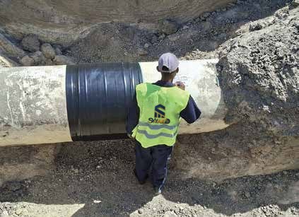 Field crew applying protective wrap to an excavated pipeline